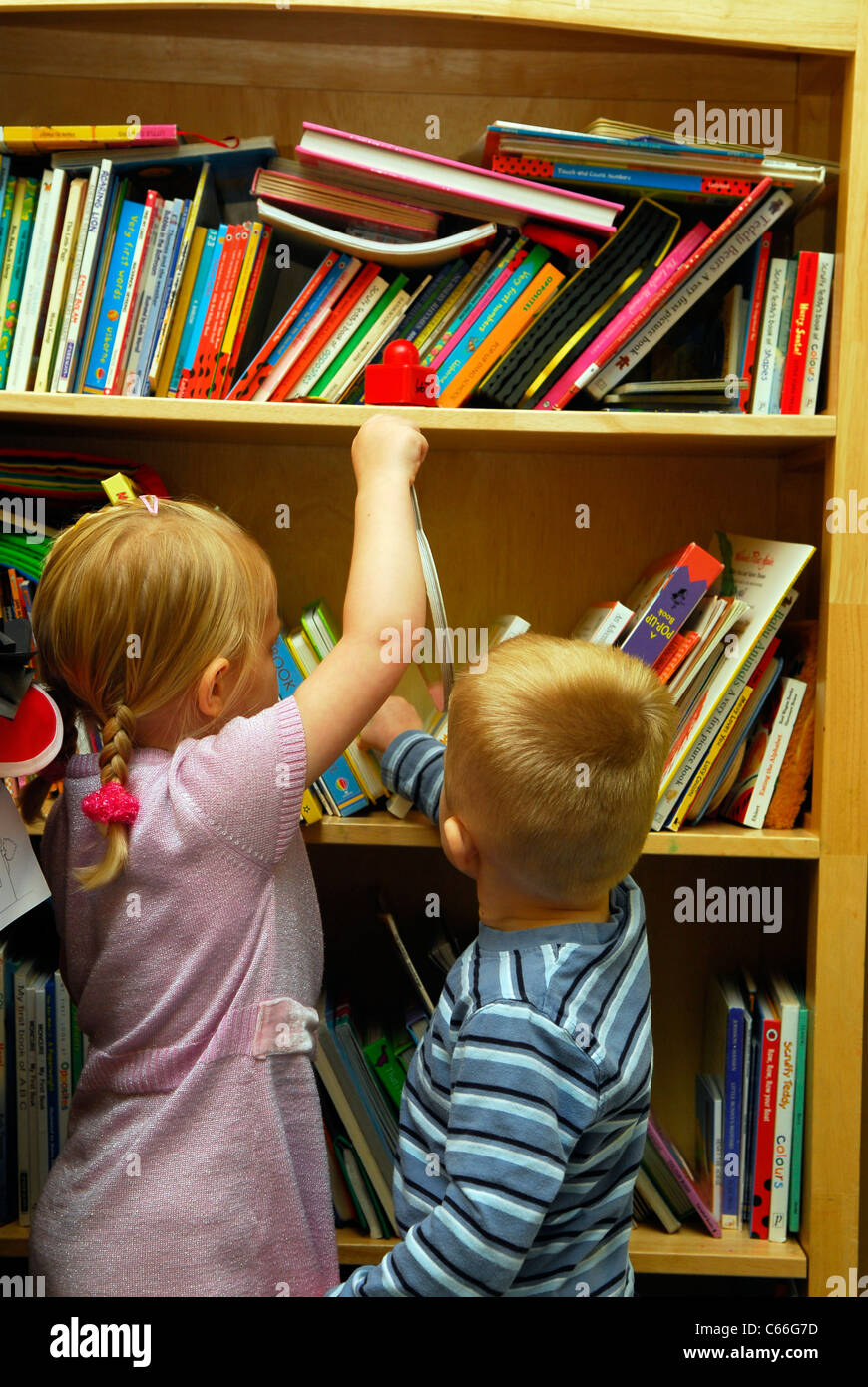 Youngsters at a creche for under 4-year olds browsing books, Northumberland, UK. Stock Photo