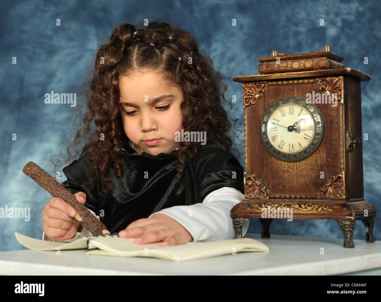 Atmospheric image of a sad lonely Girl of five doing homework next to an old style mantel place clock Stock Photo