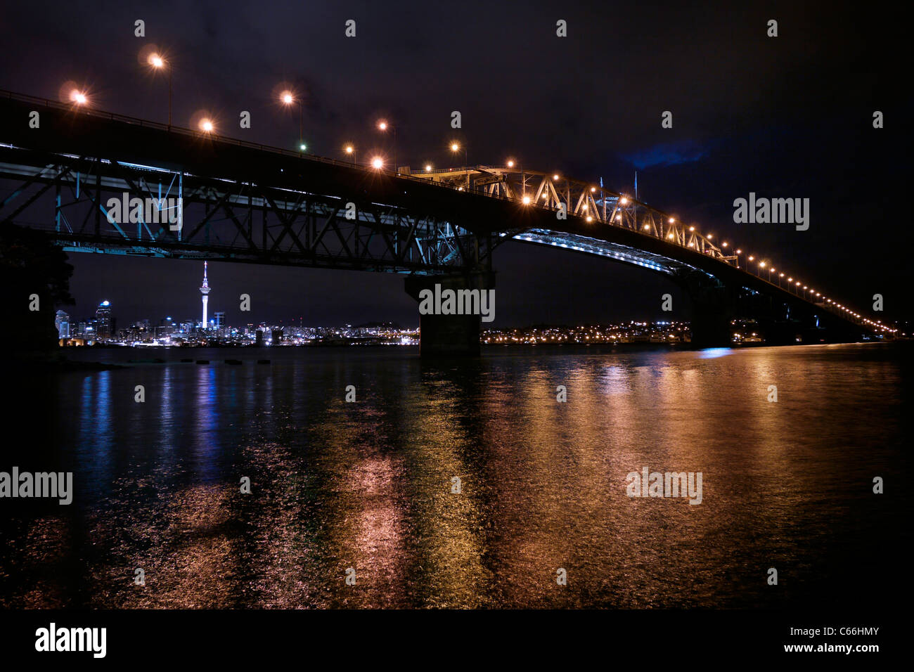 Looking at Auckland city from the North Shore at night with the Harbour Bridge in foreground Stock Photo