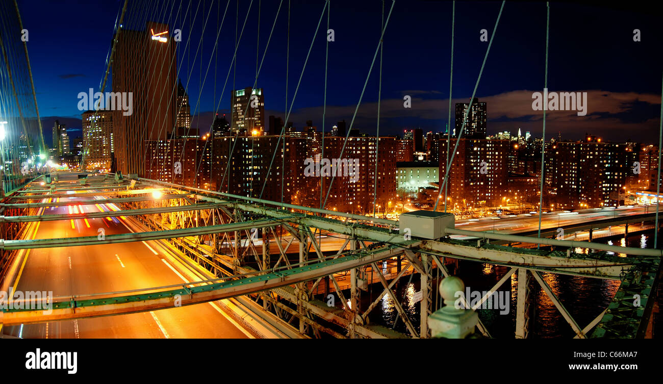 Panorama of Brooklyn bridge busy traffic at night and Manhattan skyline with skyscrapers Stock Photo