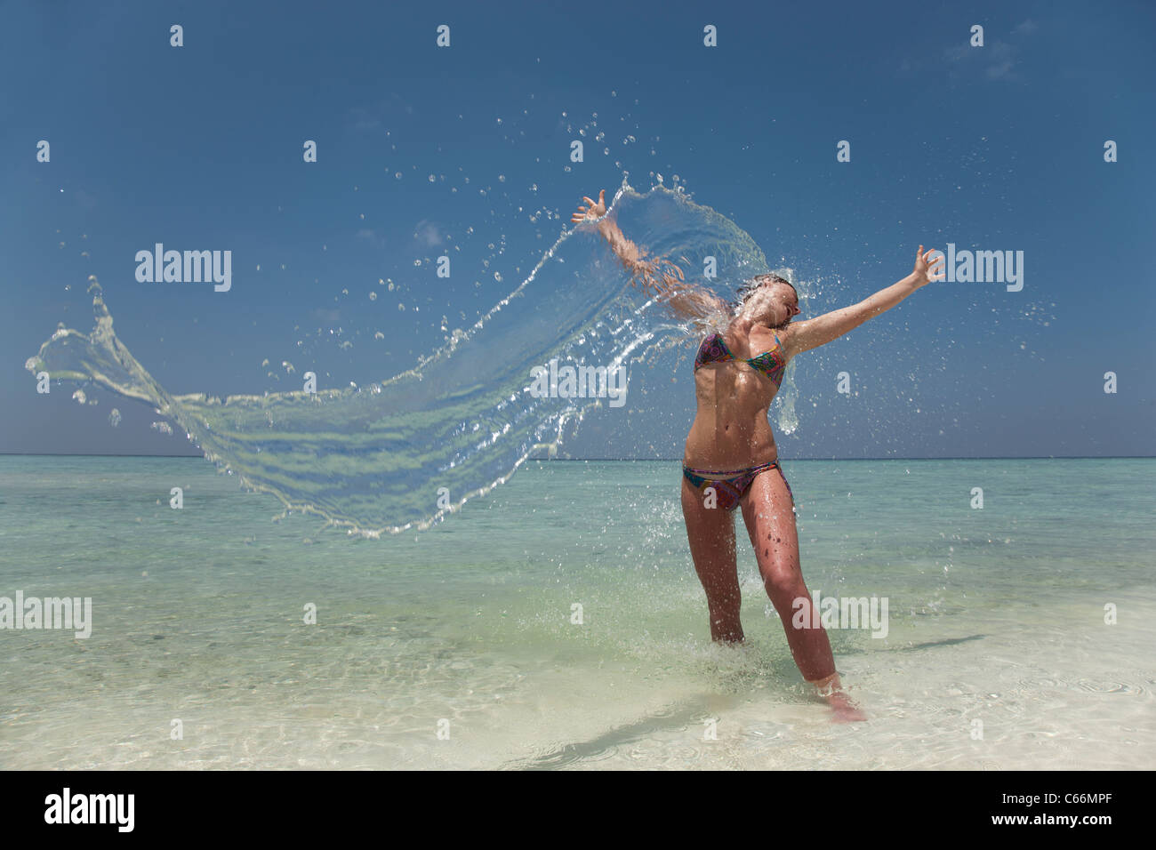 Woman splashing in water at beach Stock Photo