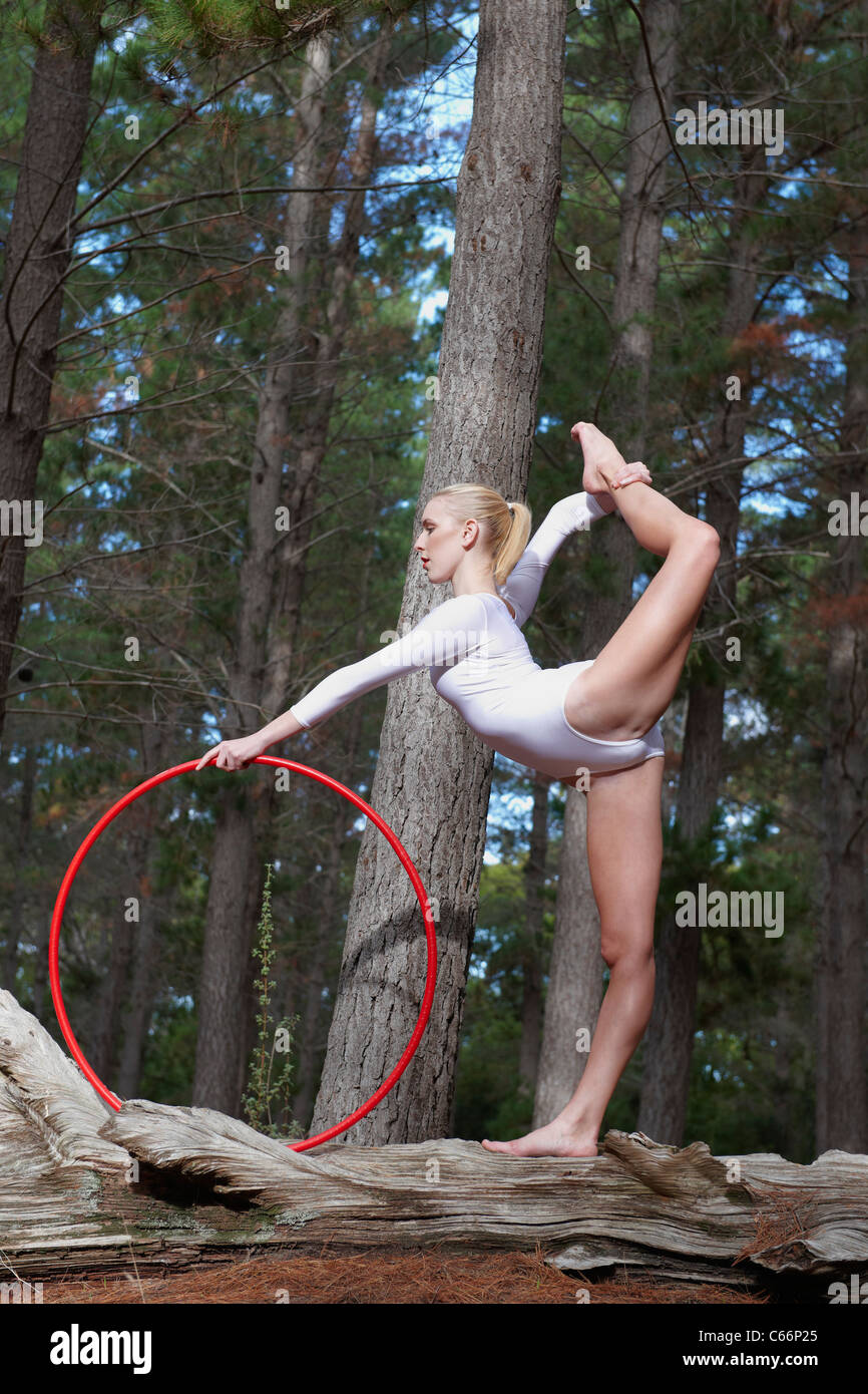Dancer posing on log in forest Stock Photo