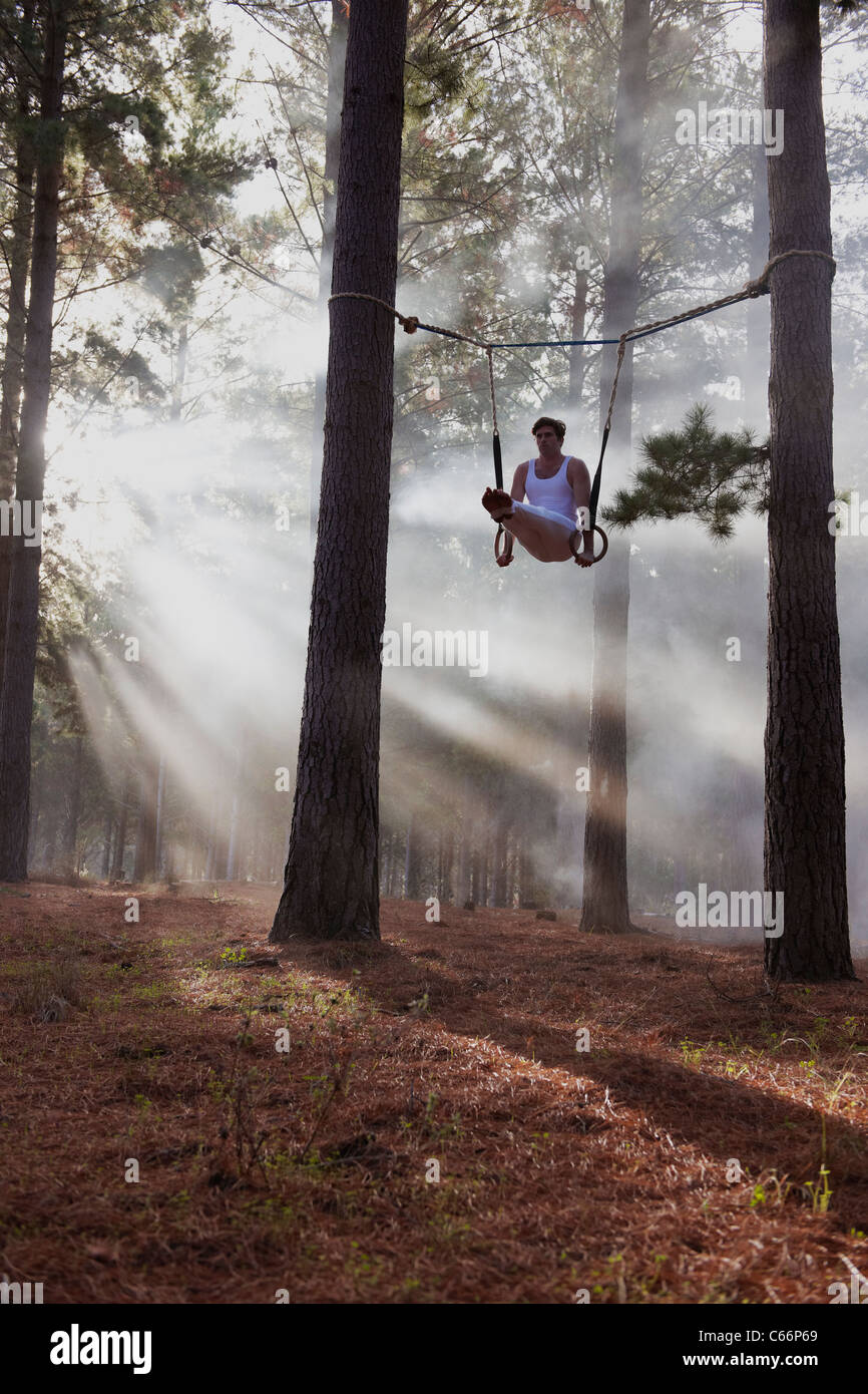 Gymnast using rings in forest Stock Photo