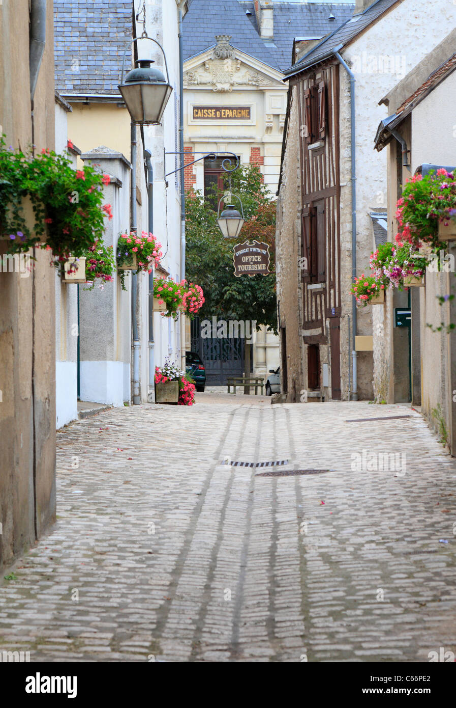 A narrow cobbled flower lined street leading to the Office de Tourisme, Tourist Office in the medieval town of Beaugency in the Loire Valley, France. Stock Photo