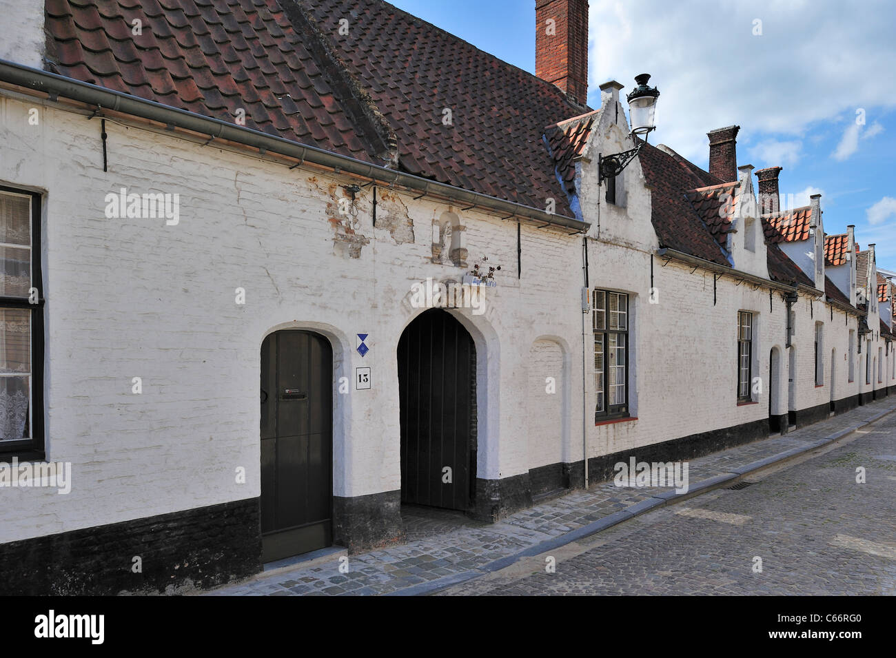 White almshouses along cobbled street in Bruges, Belgium Stock Photo