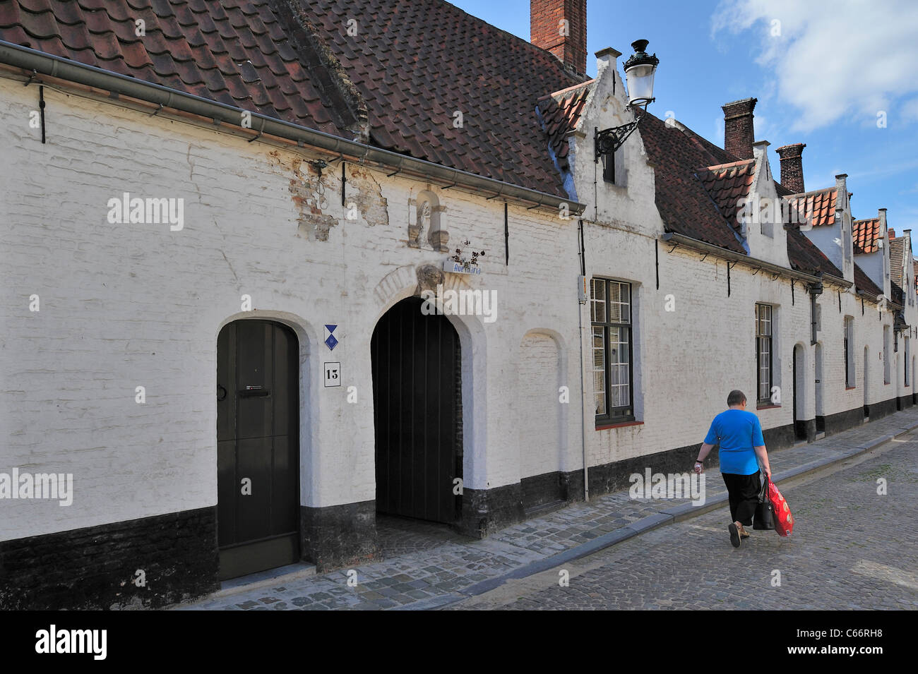 White almshouses along cobbled alley in Bruges, Belgium Stock Photo