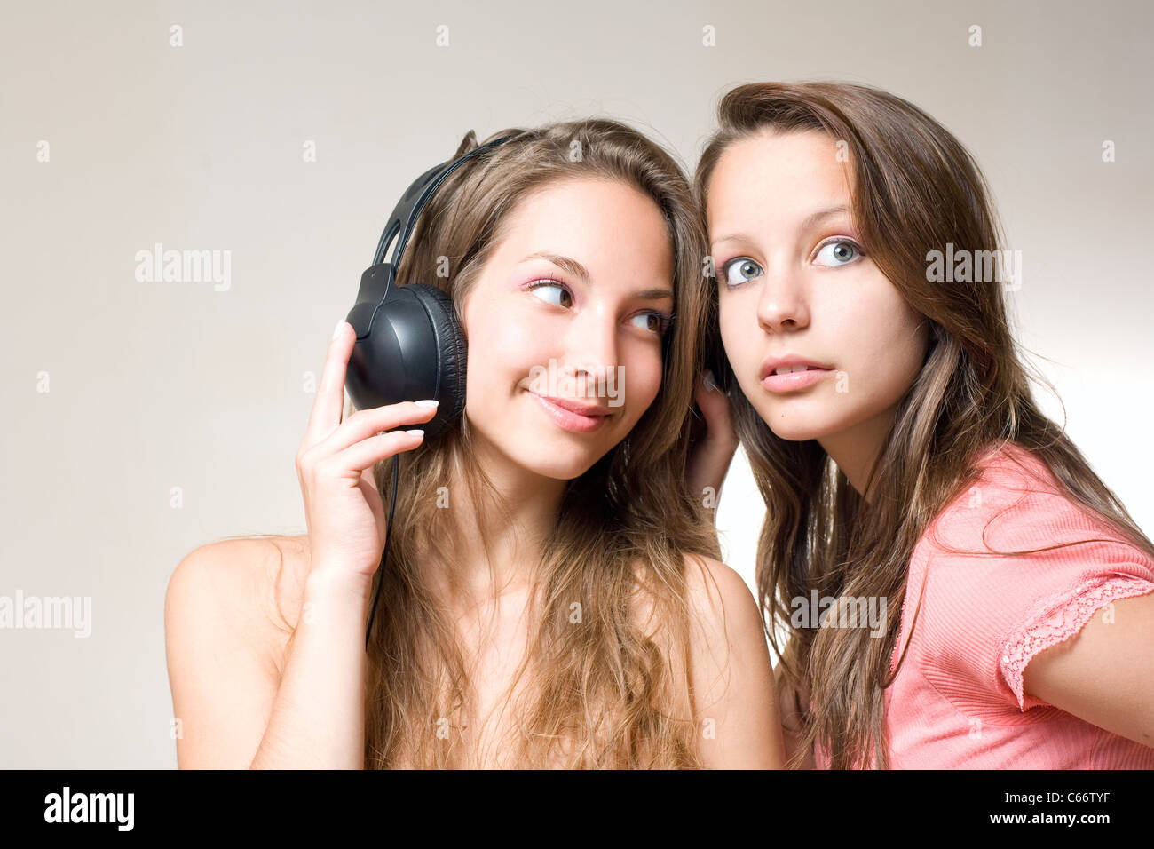 Two beautiful young brunettes sharin their music playing with their headphones. Stock Photo