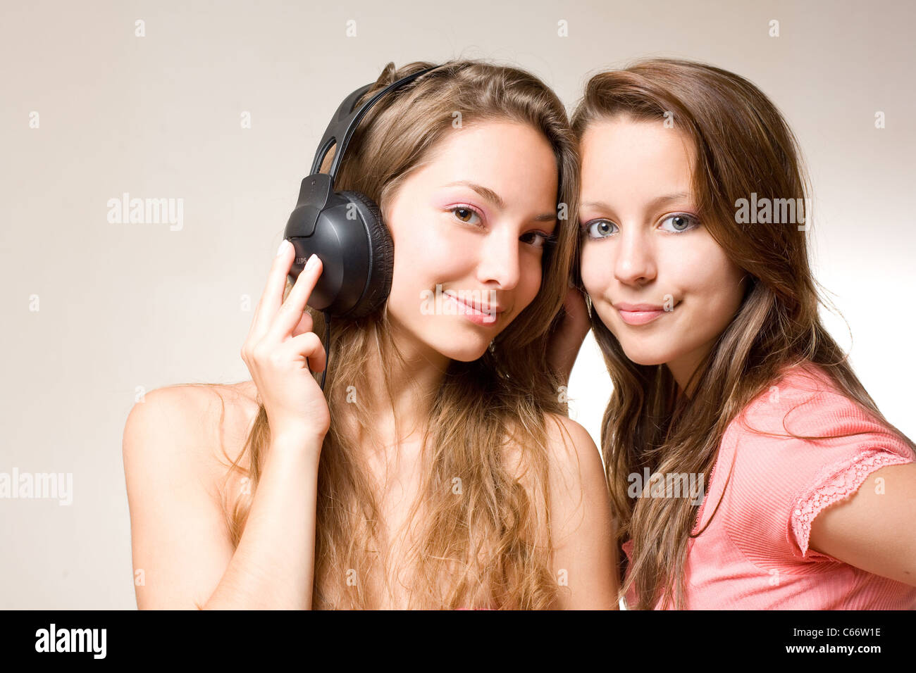 Two beautiful young brunettes sharin their music playing with their headphones. Stock Photo