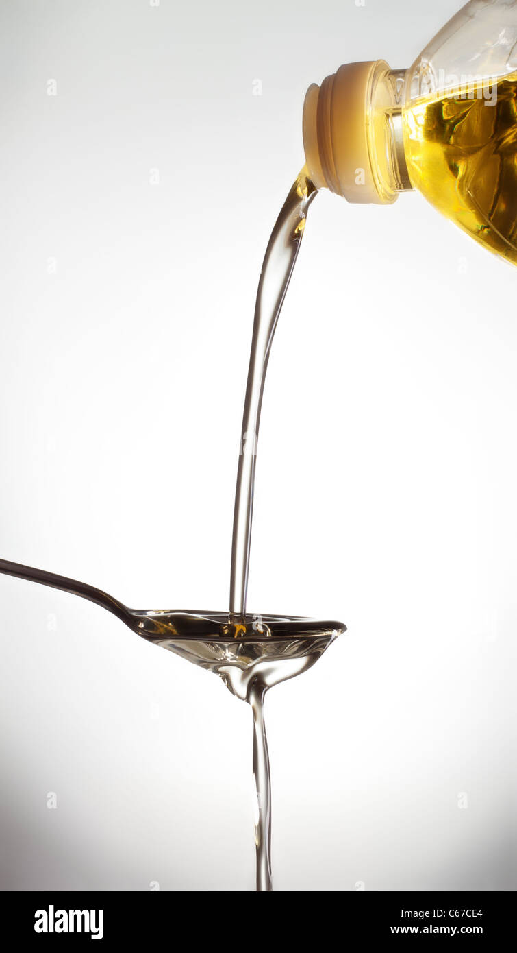 pouring olive oil on spoon, gray background Stock Photo
