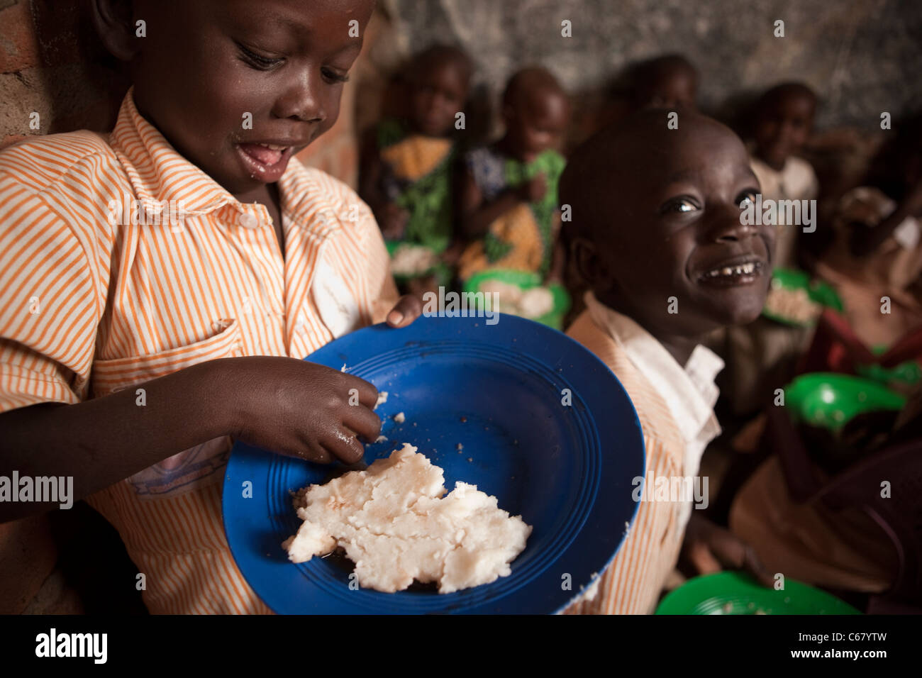 Young school children eat a meal of posho, or ugali, at a school in Amuria, Uganda, East Africa. Stock Photo
