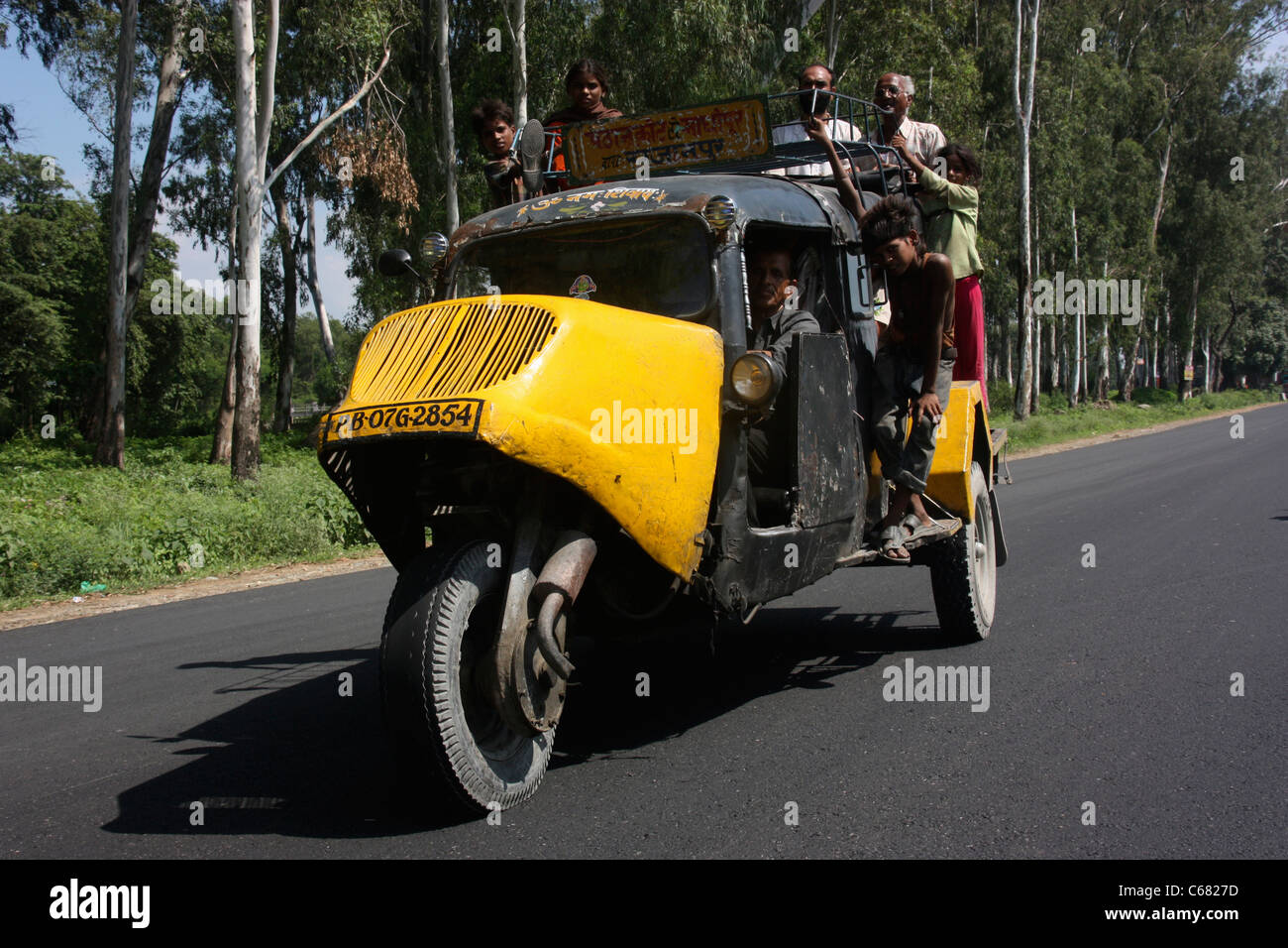 Passengers cling to an Indian Tempo three wheeler taxi bus in the Punjab India Stock Photo