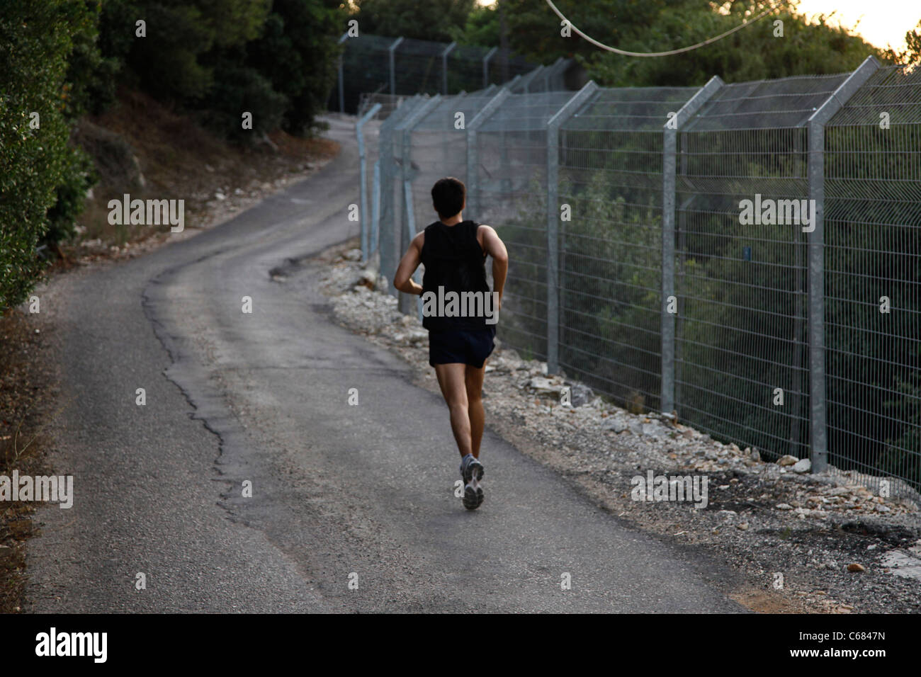 An Israeli civilian running along the border fence in Kibbutz Hanita located in the western Galilee near the border with Lebanon in Israel Stock Photo