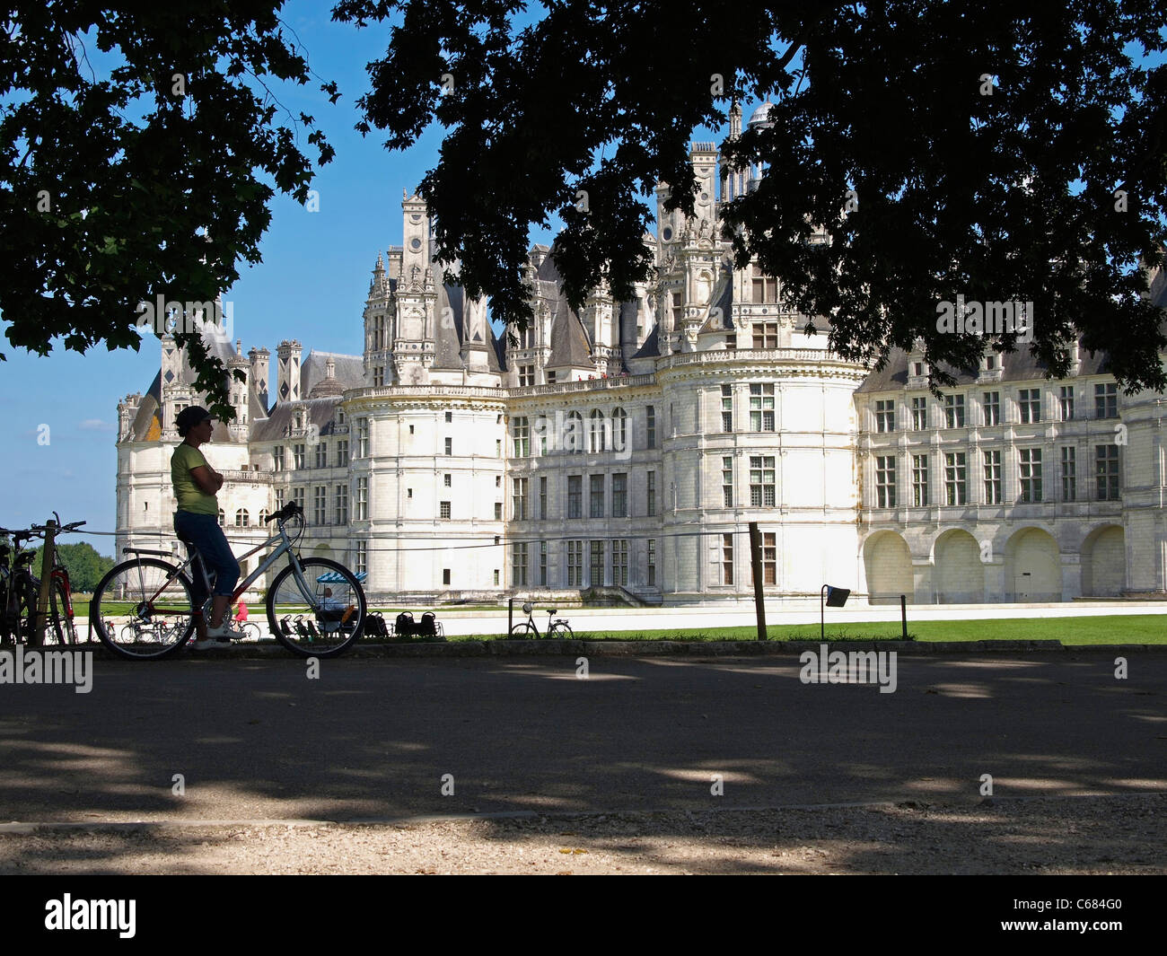 Silhouetted woman cyclist looking at Chateau royal de Chambord, Loire valley, France Stock Photo