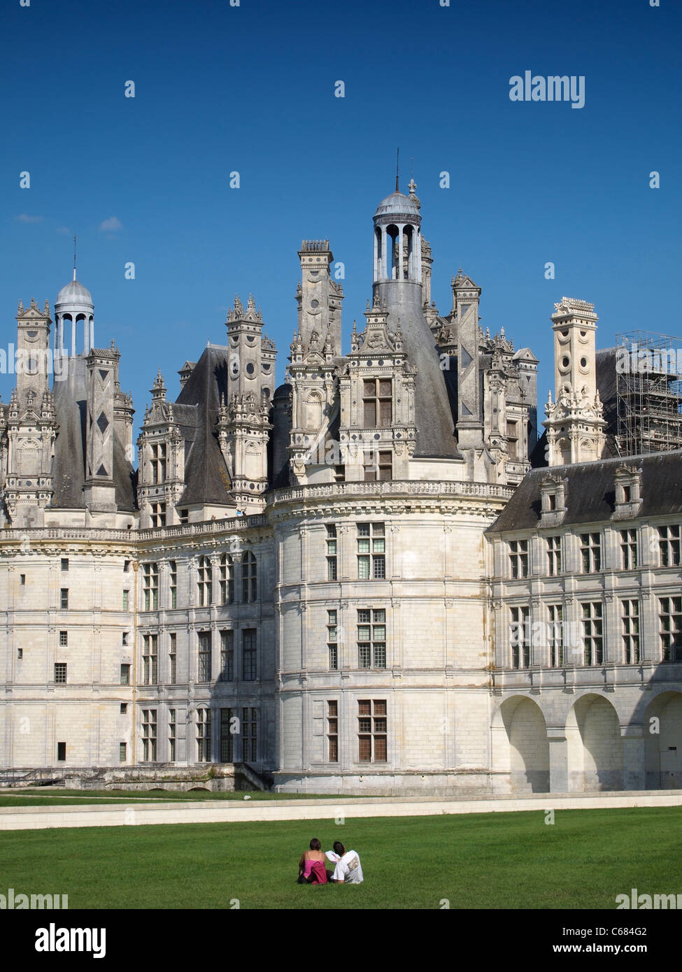 Couple sitting in the grass admiring the magnificent Chateau Royal de Chambord, Loire valley, France Stock Photo