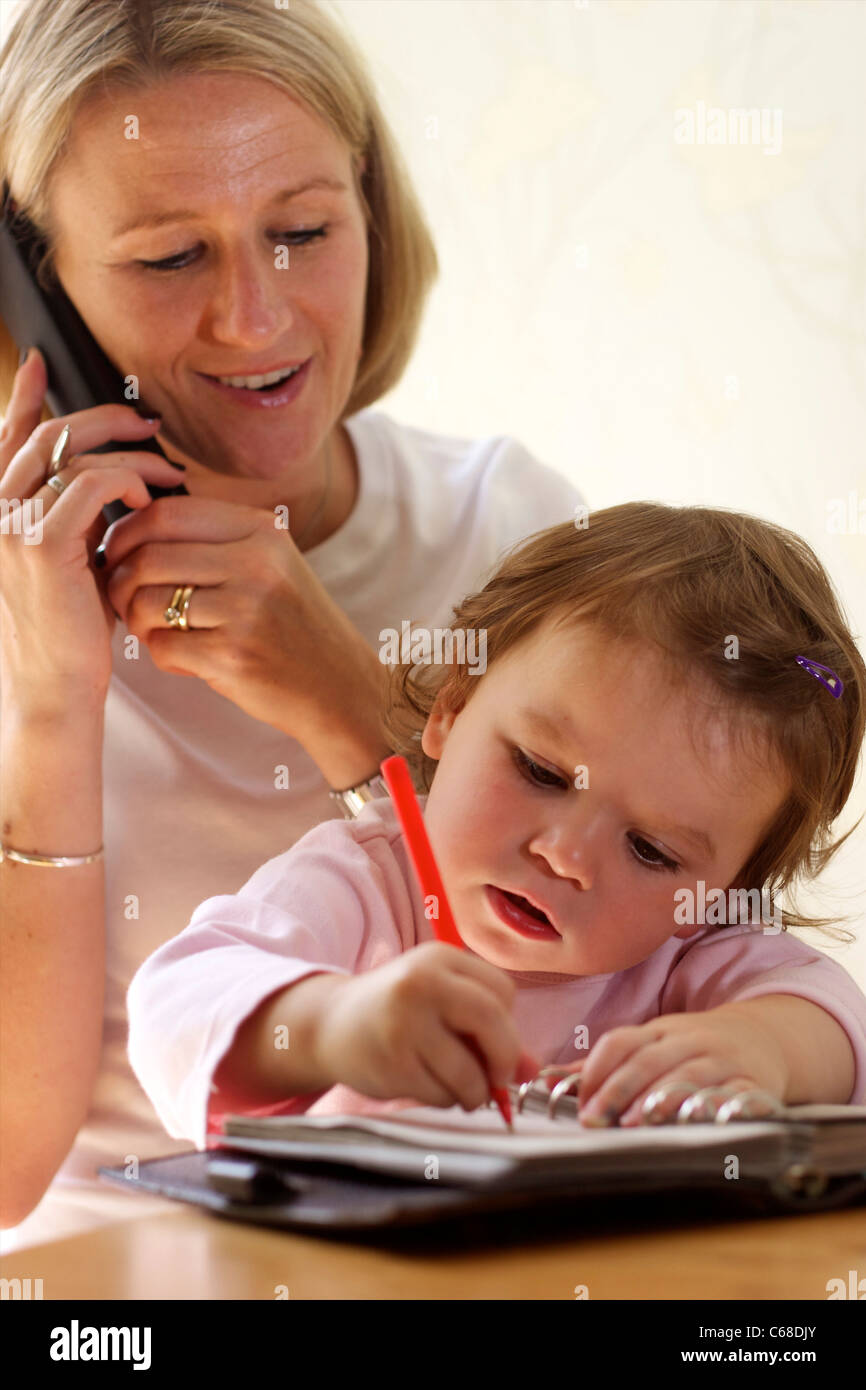 Mother on the phone and 2 year old child Stock Photo