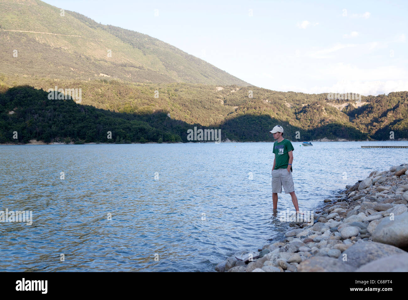 teenager boy standing on lake shore Stock Photo
