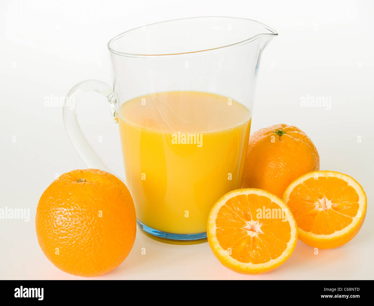 ein Glaskrug mit Orangensaft, davor liegen Orangen | a glass jug with orange juice, in front are oranges Stock Photo