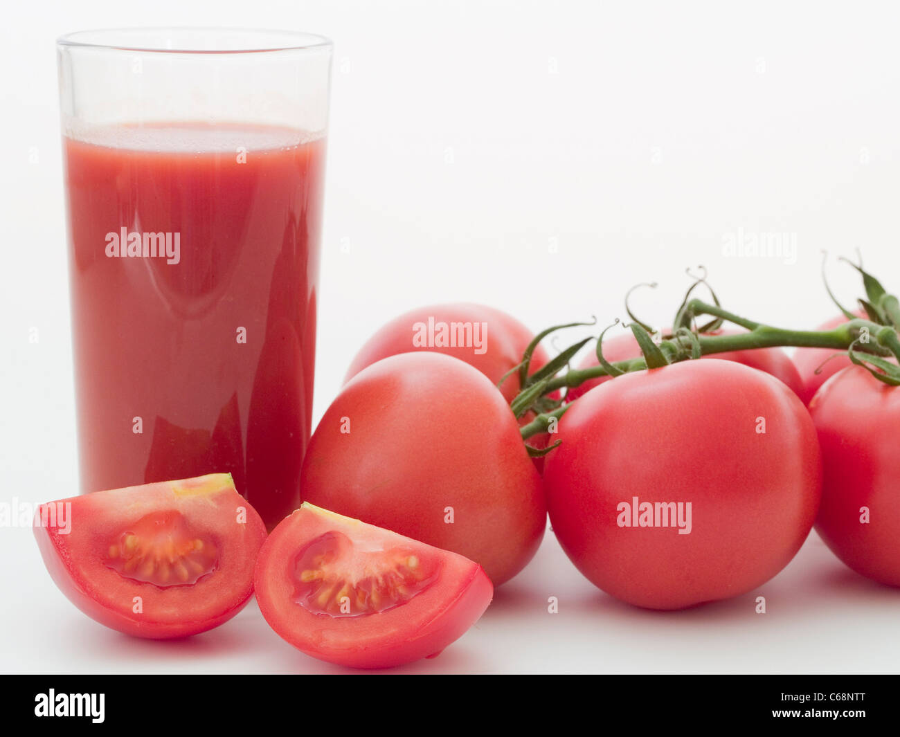 ein Glas Tomatensaft, daneben liegen Strauchtomaten | a glass tomato juice, besides are bush tomatoes Stock Photo