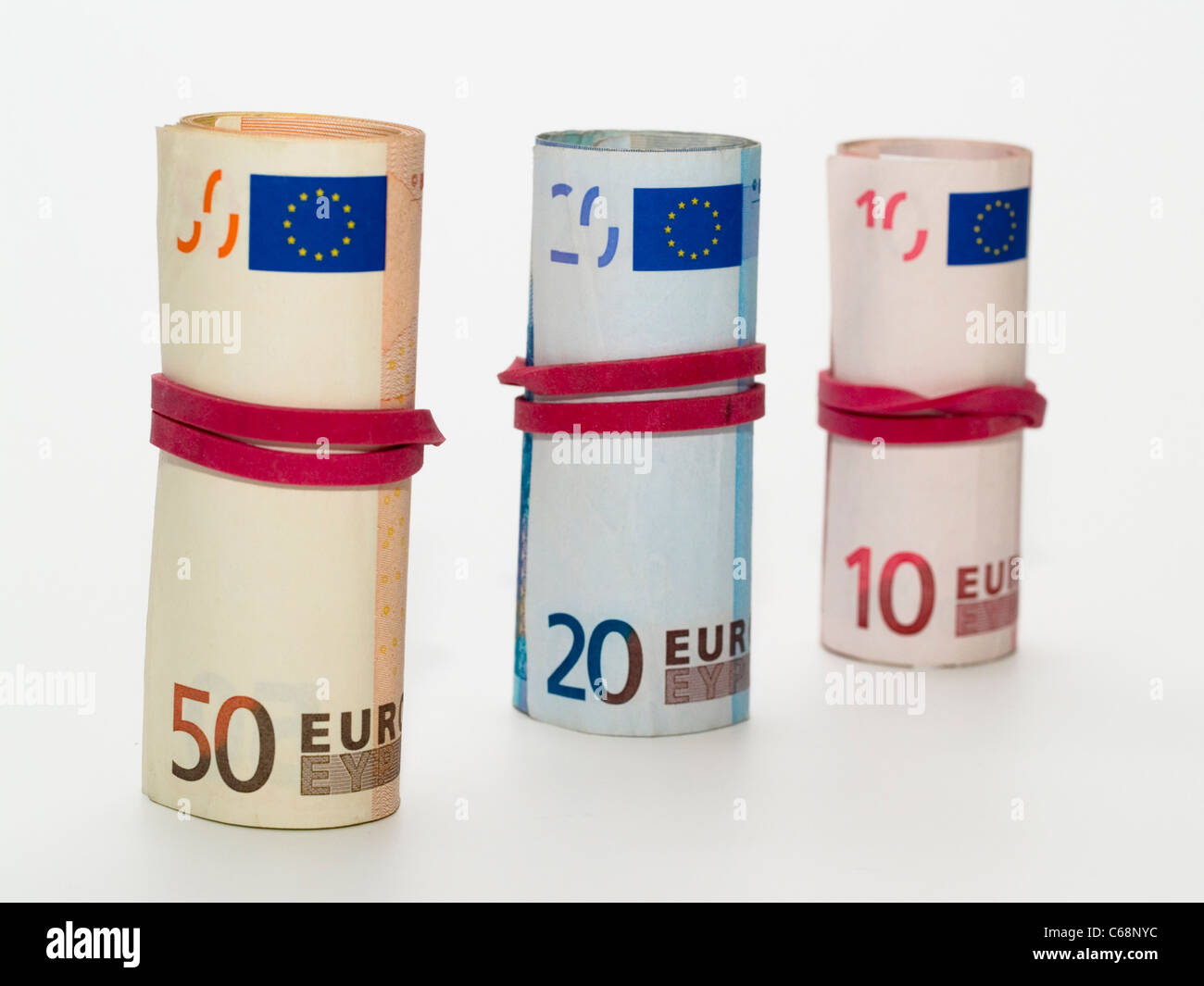 drei gerollte Geldbündel mit 10, 20 und 50 Euro-Scheinen | three rolled bundles of money with 10, 20 and 50 euros banknotes Stock Photo