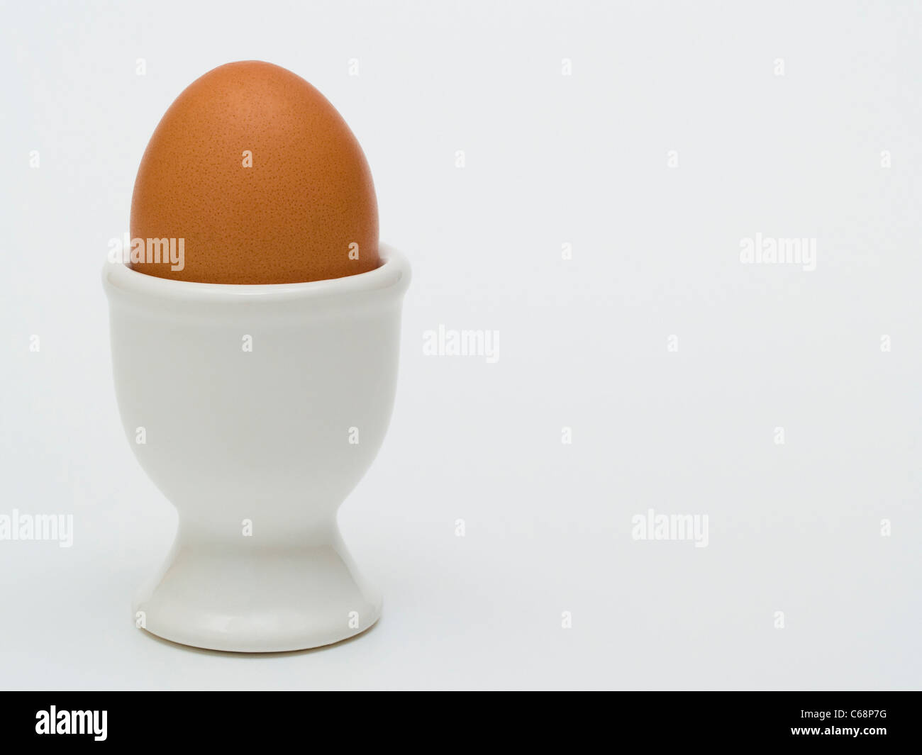 ein braunes Hühnerei steht in einem Eierbecher | one eggcup with a brown hen's egg Stock Photo