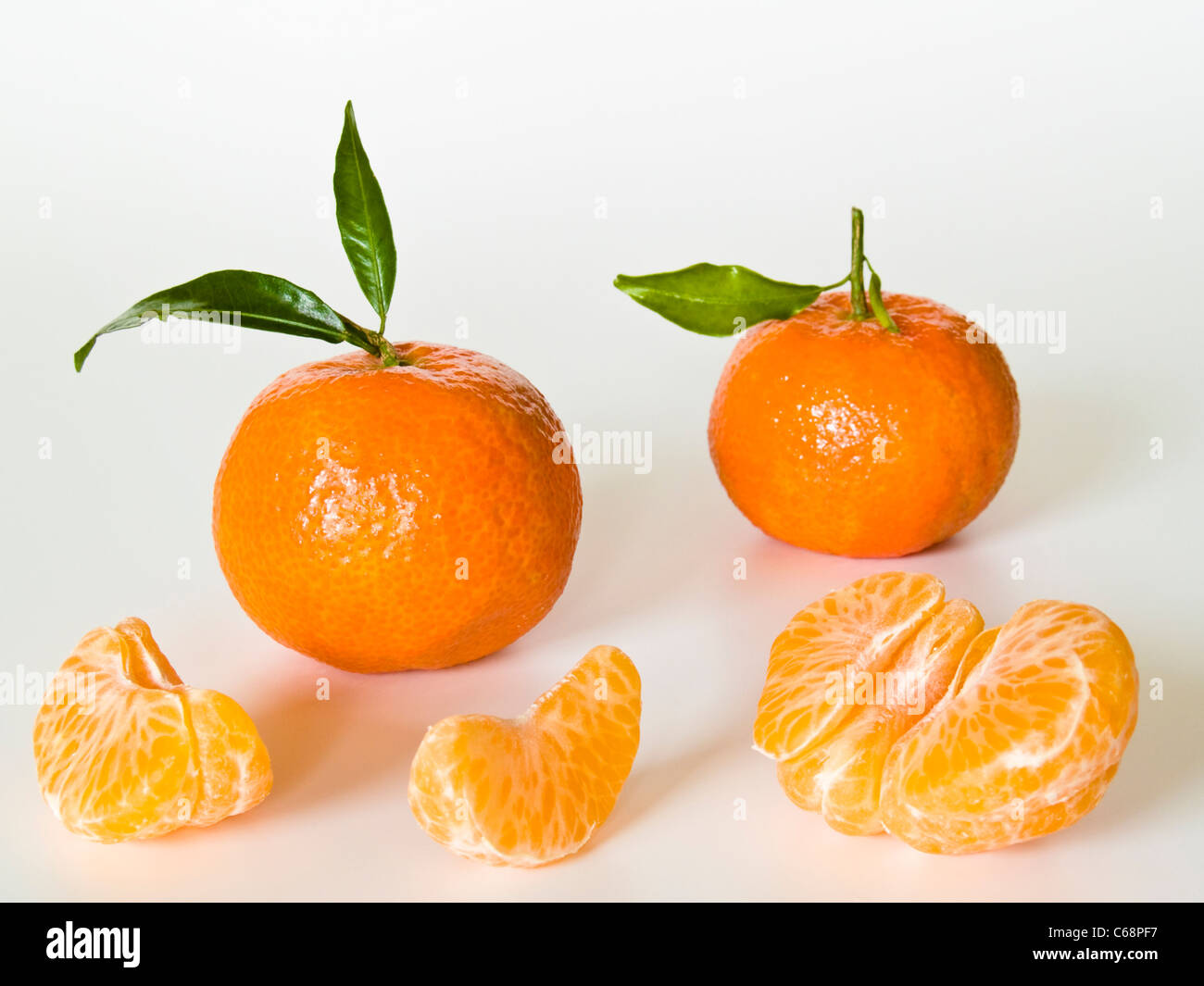 Zwei Clementinen, dabei liegen Fruchtstückchen | two Clementines, beside are pieces of fruit Stock Photo