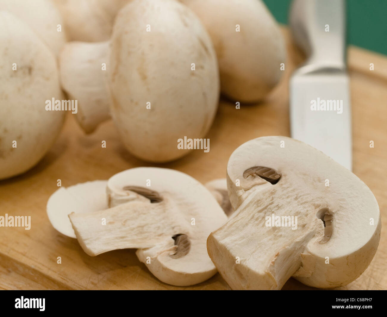 Mushrooms are cut on a wood board,  a knife in the background Stock Photo