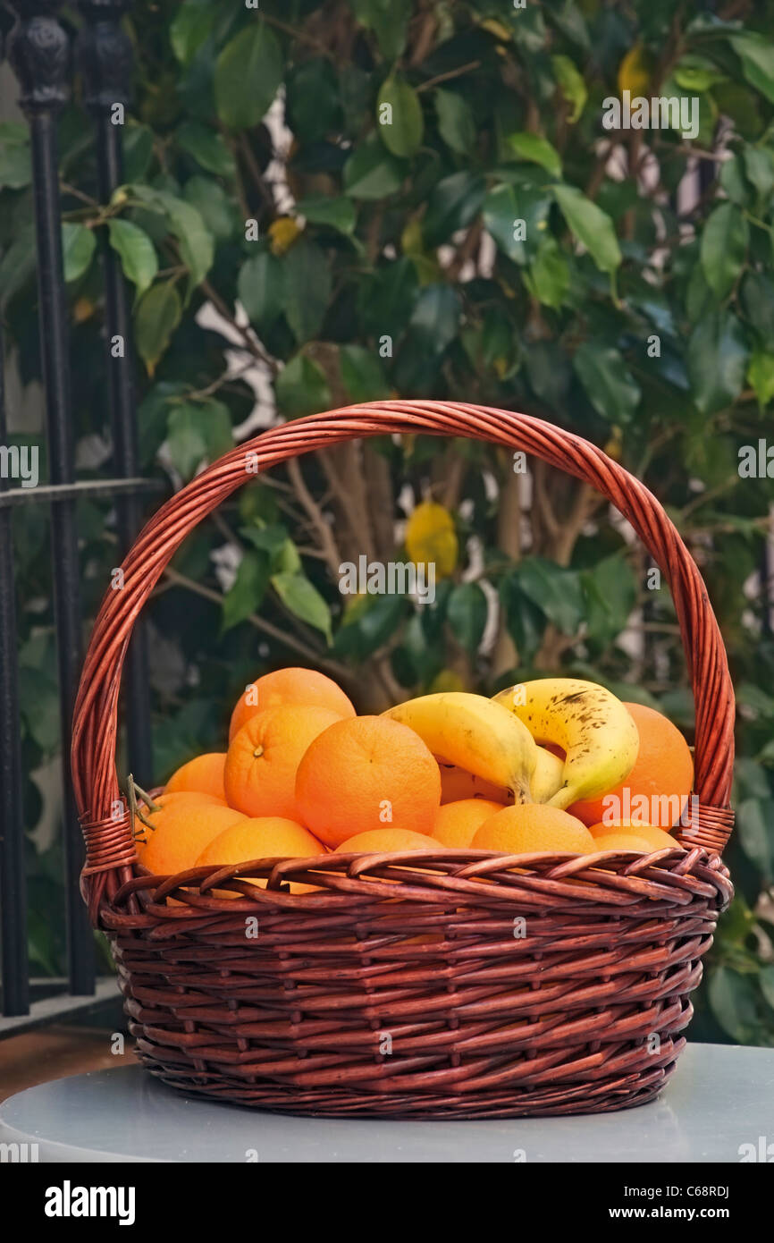 Basket of oranges and bananas on table Stock Photo