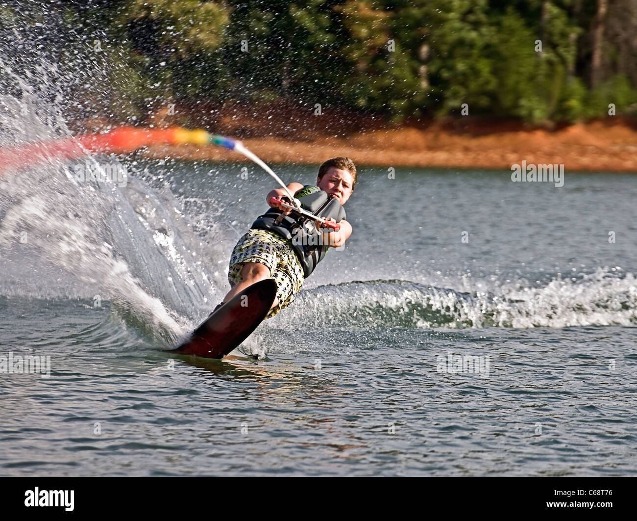 A preteen boy on a slalom ski cutting across the wake with an expression of total concentration. Stock Photo