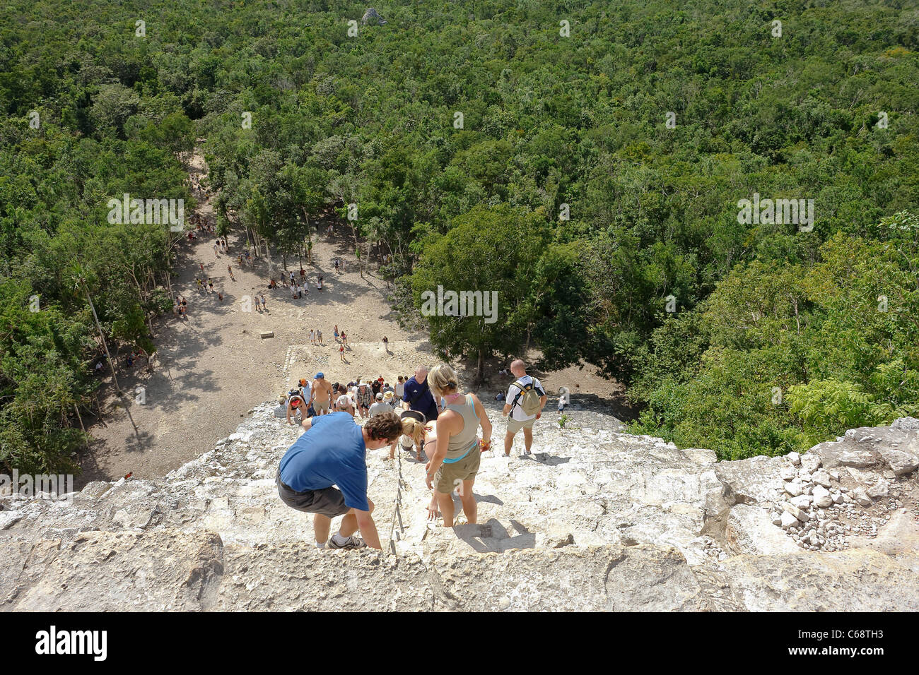 Tourists climb up and down dangerous temple steps to a Mayan temple at