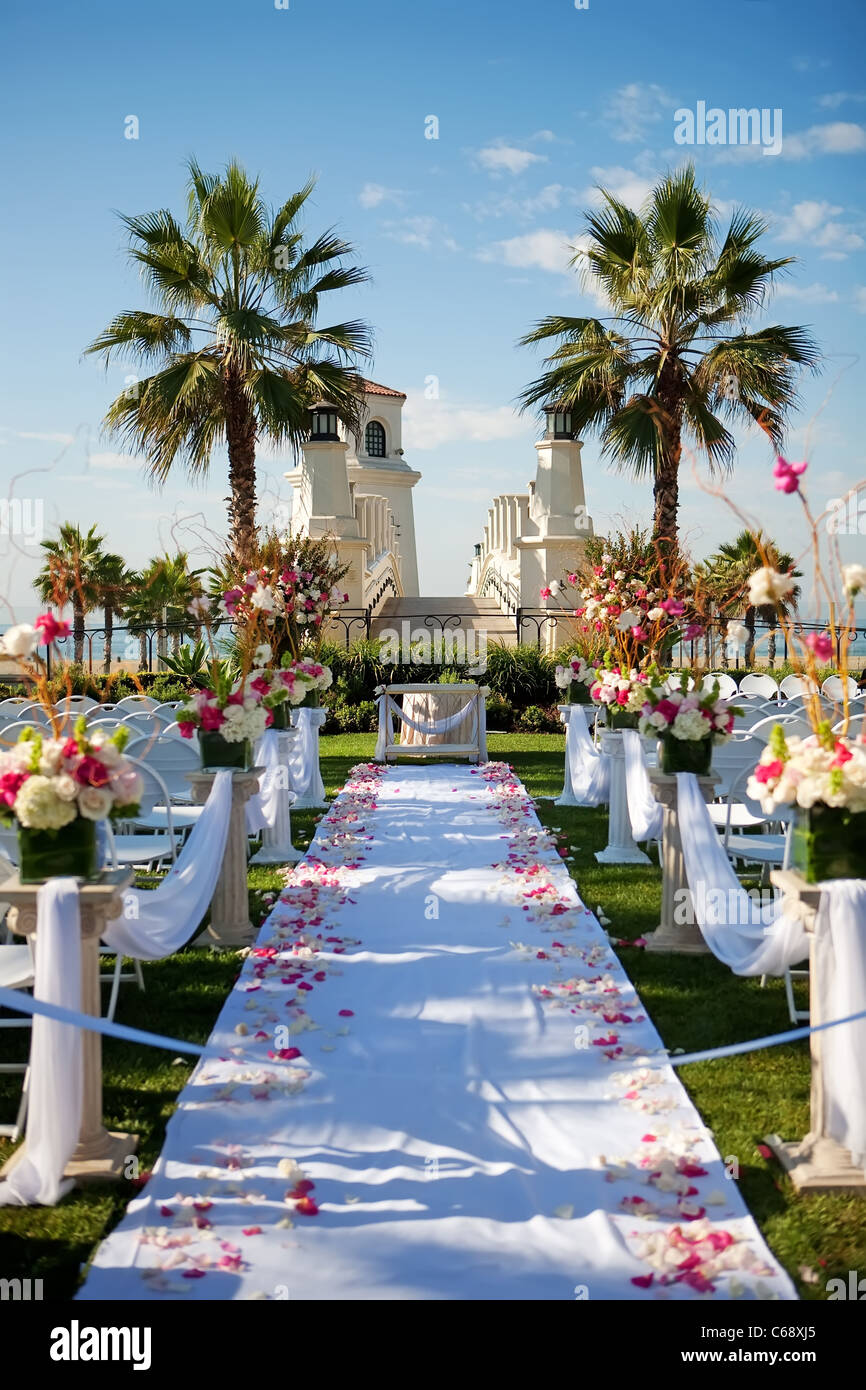 Outdoor wedding by the beach with palm trees, rose petals on isle Stock Photo