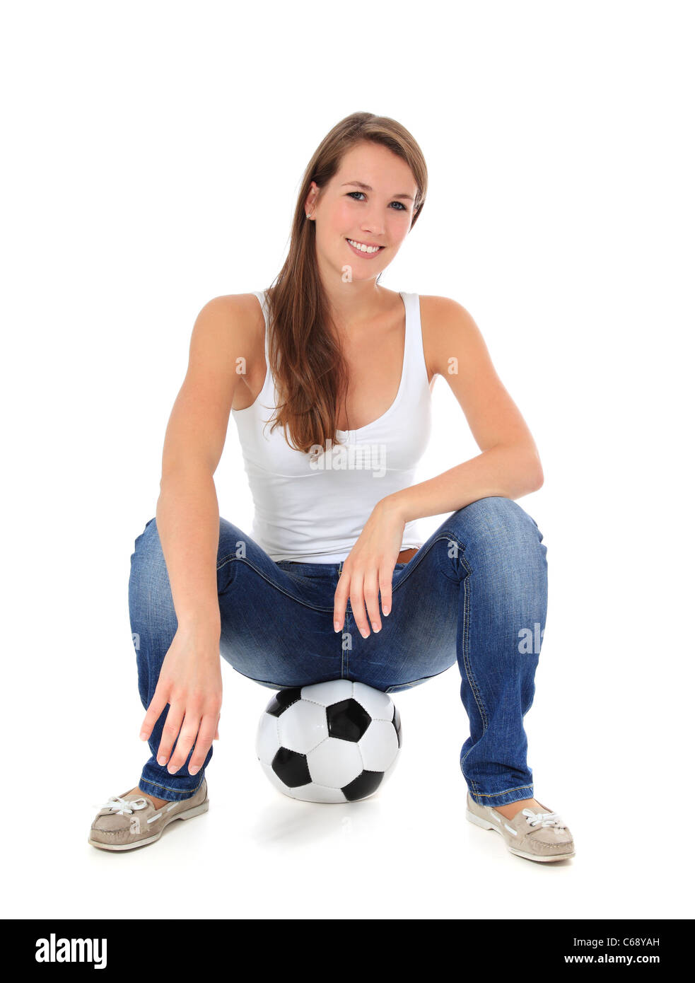 Attractive young woman sitting on soccer ball. All on white background