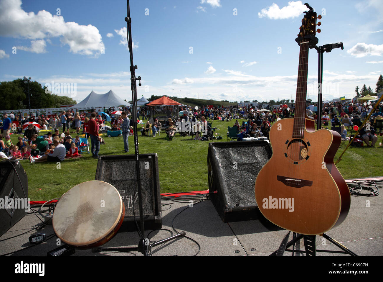 takamine acoustic electic guitar bodran drum and monitor speakers on stage at a summer outdoor festival Saskatoon Saskatchewan Stock Photo