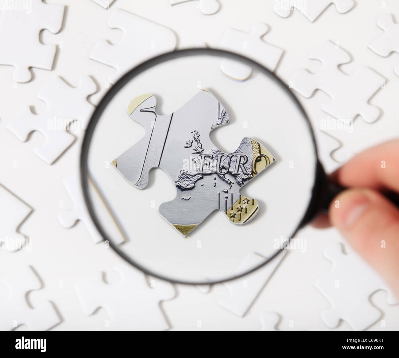Concept of a person using magnifier to check piece of puzzle with euro topic. Stock Photo