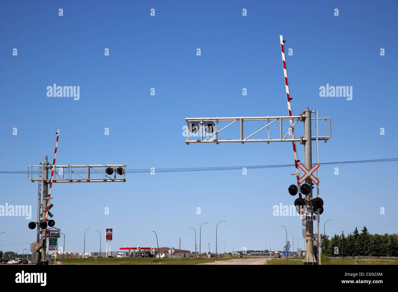 high level railroad crossing lights and barriers against blue sky Saskatchewan Canada Stock Photo