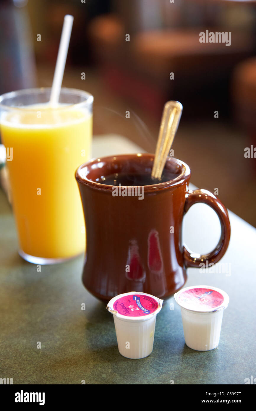 mug of black coffee with portions of 2% milk and orange juice Stock Photo
