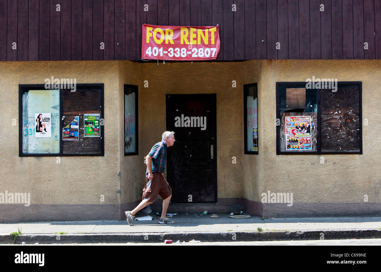 A man walks past a boarded up shop, Central Falls, Rhode Island Stock Photo