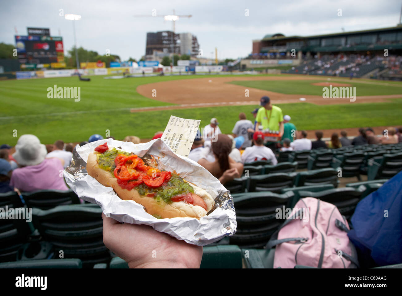 holding hot dog and game ticket sitting in the stand at shaw park baseball stadium formerly canwest home to winnipeg goldeyes Stock Photo