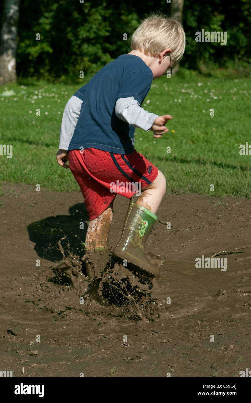 Boy Jumping In Muddy Puddle Stock Photo