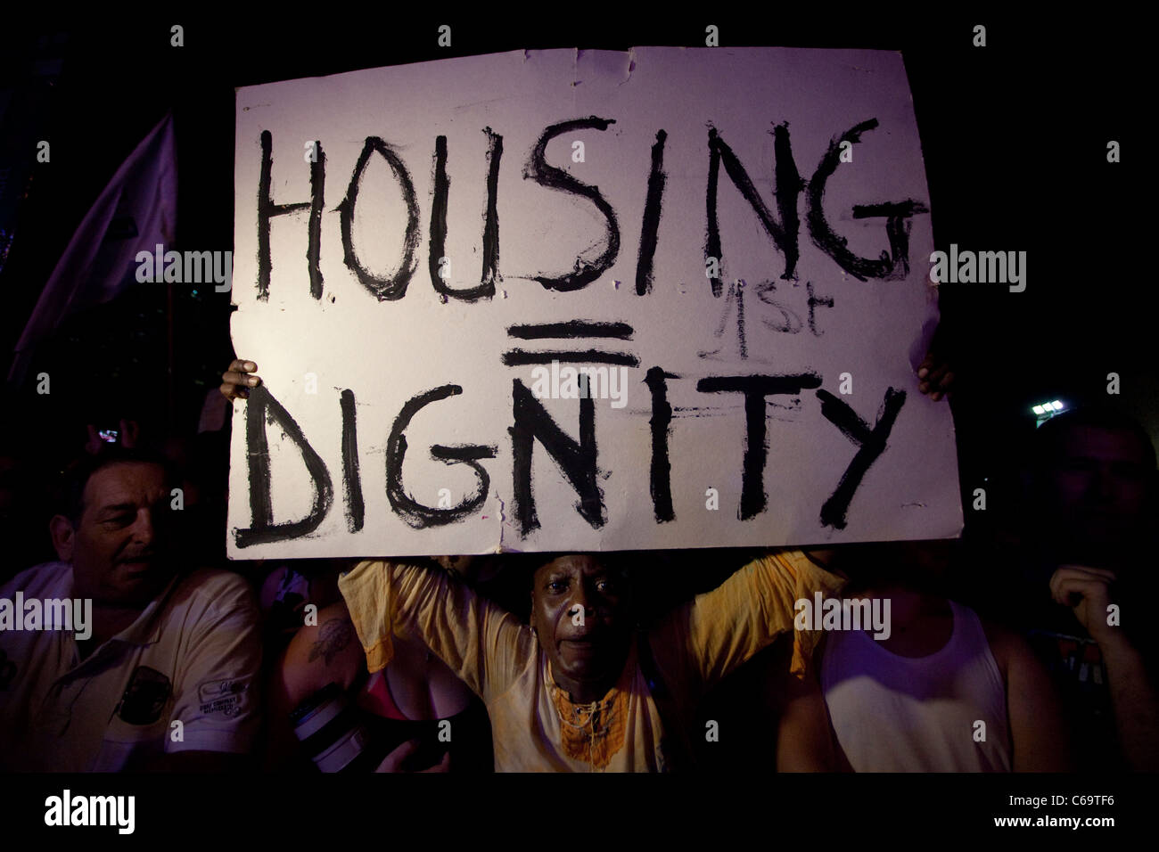 An African migrant holds a placard which reads ' Housing = Dignity' during a protest against high cost of living in Central Tel Aviv Israel. The social justice protest also named the Tents protest were a series of demonstrations in Israel beginning in July 2011 involving hundreds of thousands of protesters from a variety of socio-economic opposing the continuing rise in the cost of living particularly housing. Stock Photo