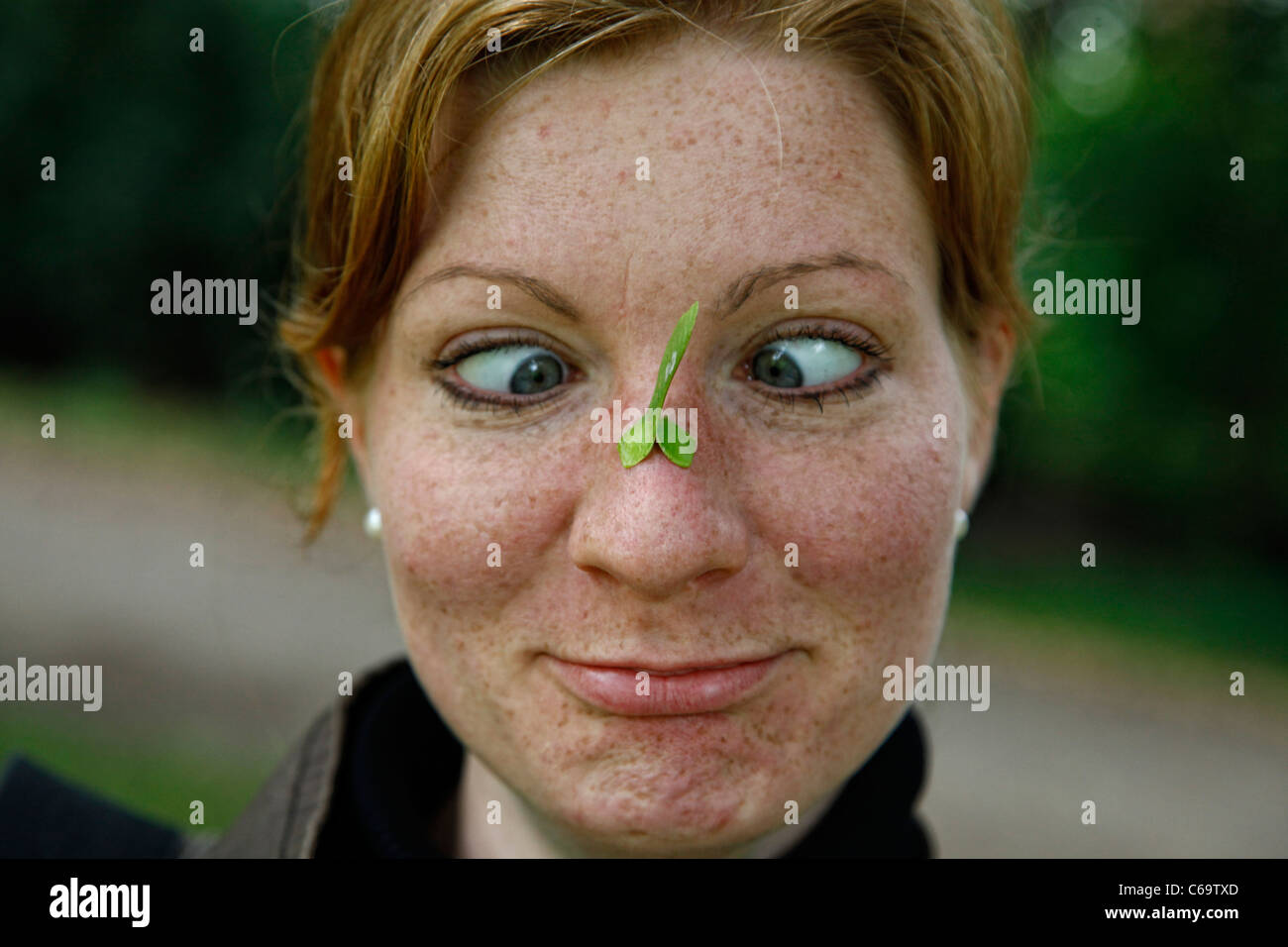 Woman with a leaf on her nose pulling funny face with eyes crossed Stock Photo