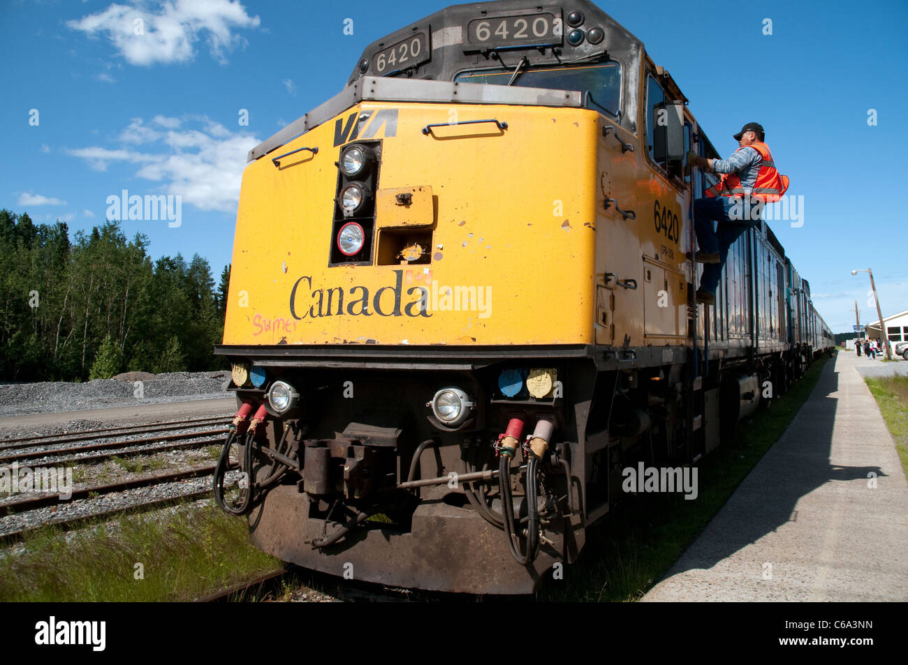 A train conductor mounts a locomotive pulling a passenger train in the northern Canadian town of Thompson, in Manitoba, Canada. Stock Photo