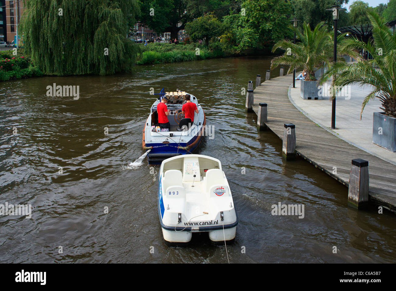 Motor boat towing pedalos on Singel Gracht in Amsterdam Stock Photo
