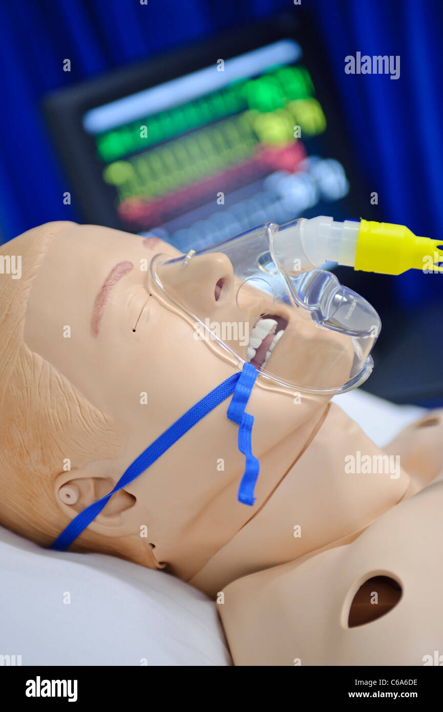 dummy patient simulated mannequin wearing oxygen mask in hospital bed vitals status monitor in background Stock Photo