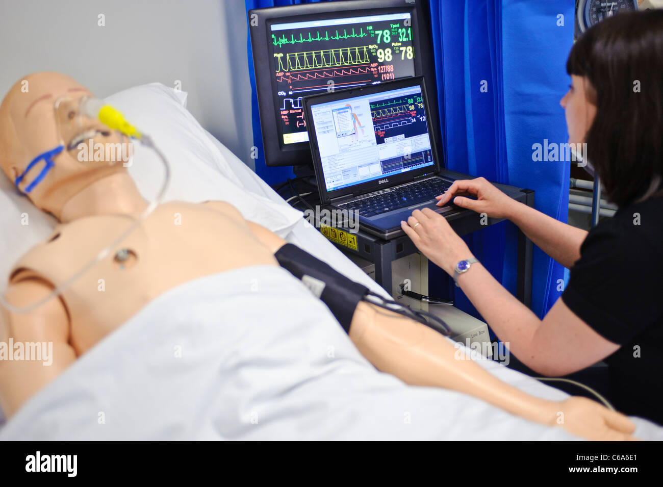 nurse running simulated dummy patient mannequin tests in hospital bed ward setting Stock Photo