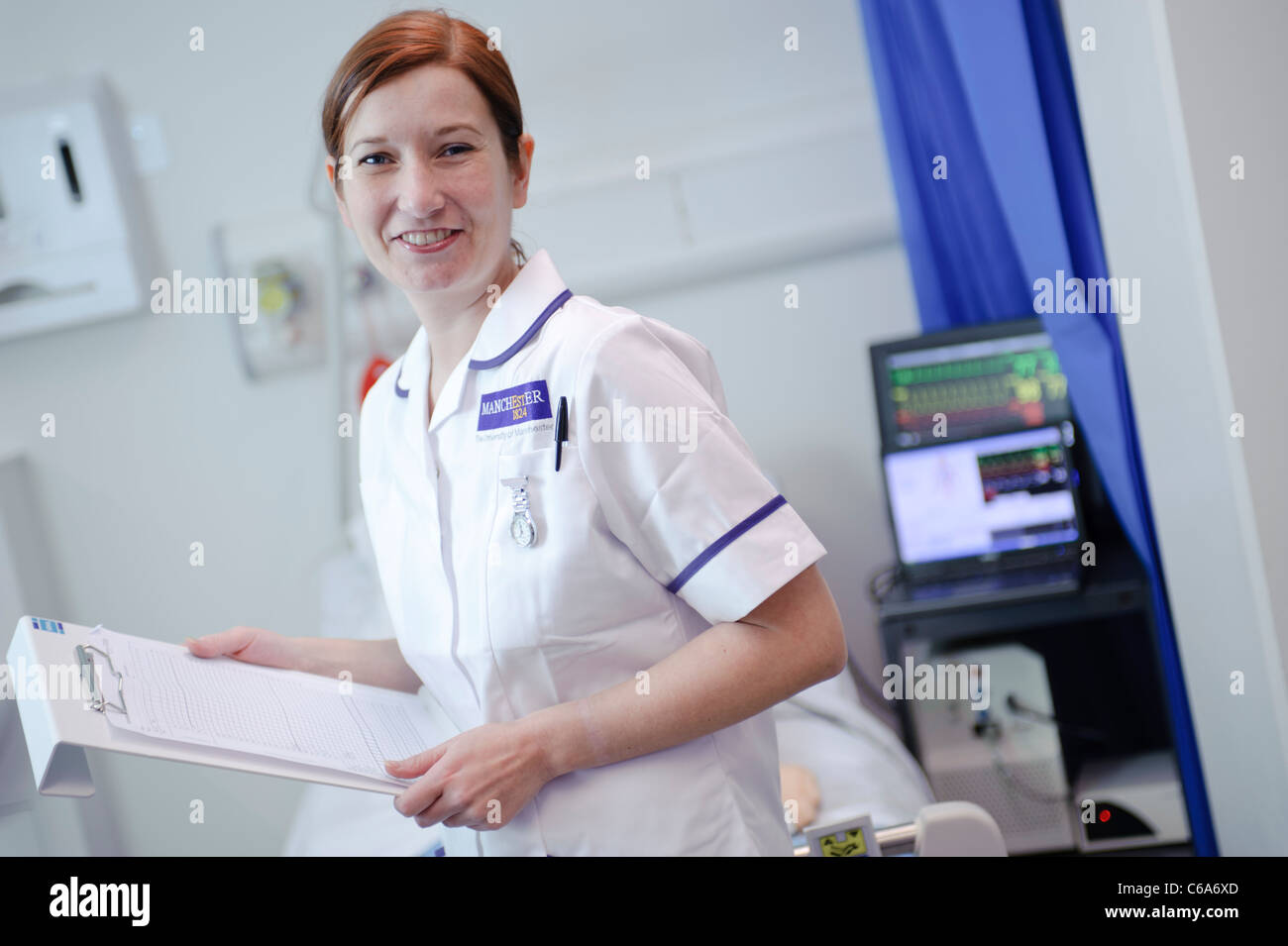 female white student nurse with patient chart on hospital ward Stock Photo
