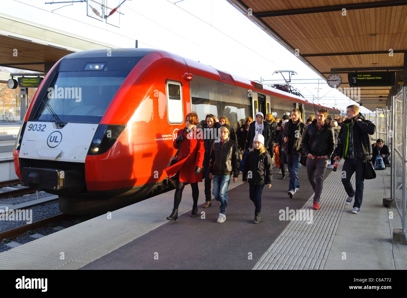 Fast higher-speed commuter train at a station with crowds of passengers on the platform Stock Photo