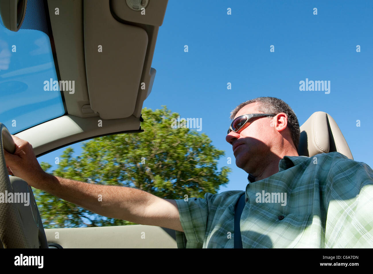 Man driving a renault megane coupe cabriolet with the roof down in summer. Stock Photo
