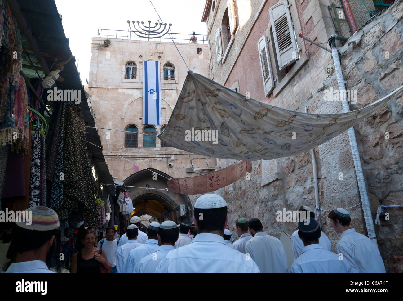 group of settlers wearing white shirts on Shabat walking by Sharon's house with israeli flag. muslem Quarter. Jerusalem Old City Stock Photo