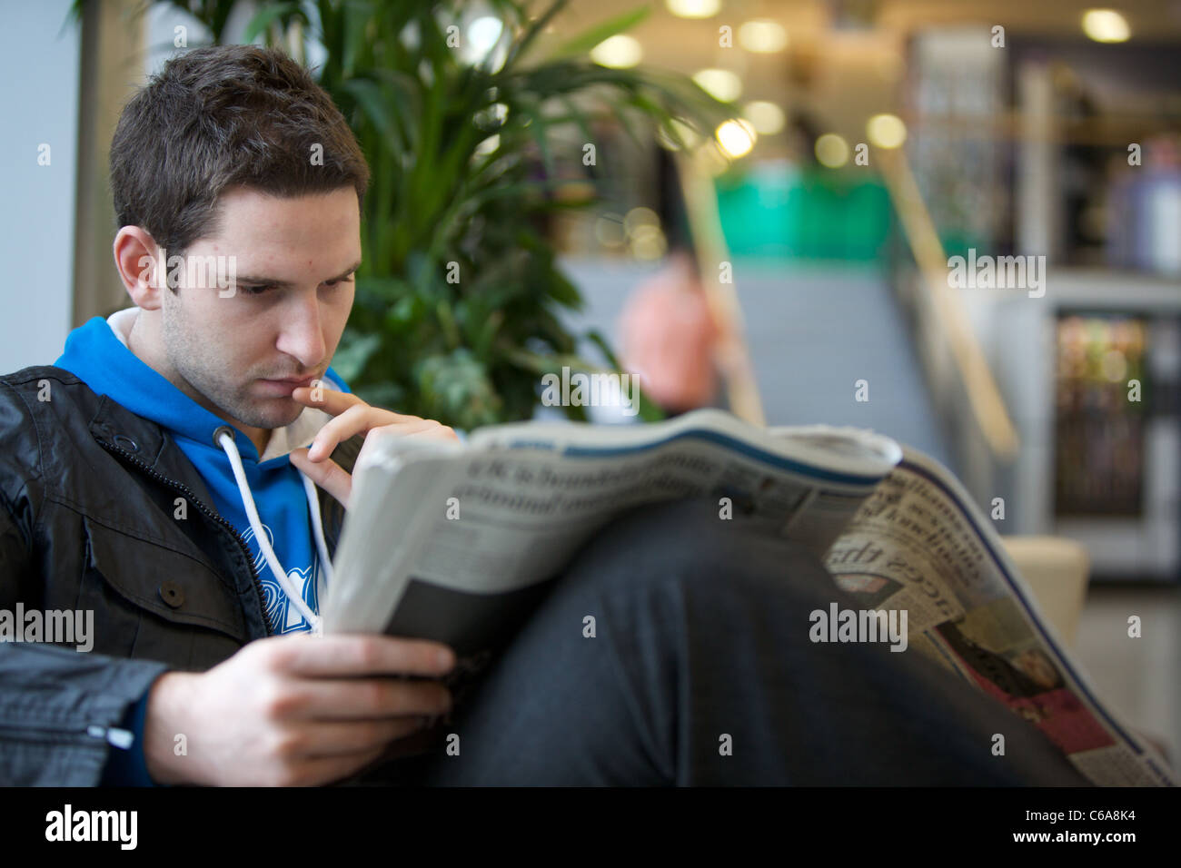Young male, man reading a newspaper Stock Photo - Alamy