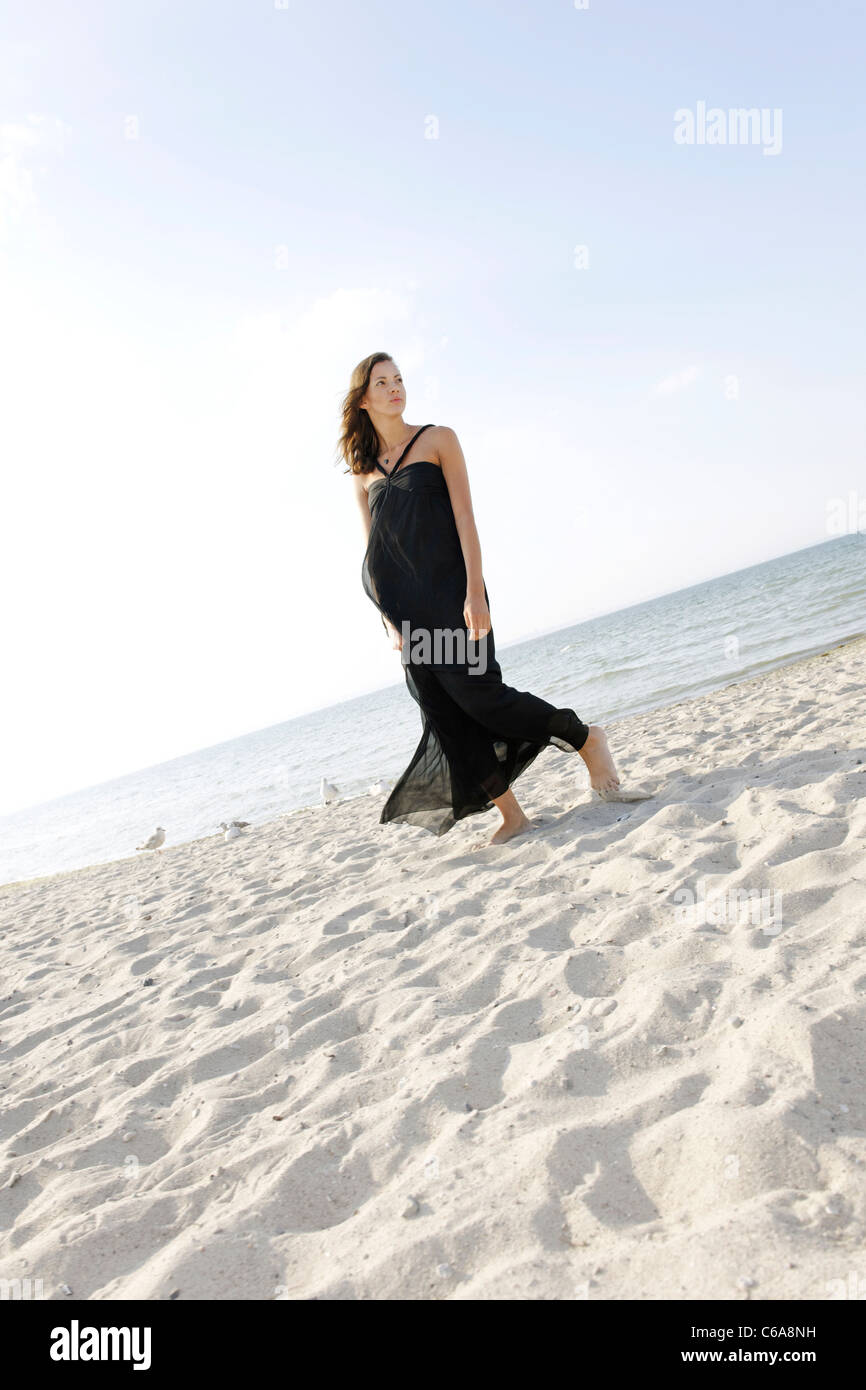 Young woman, 20+, standing in a long dress on the beach, lifestyle, sensuality, space, lightness, Niendorf at the Baltic Sea Stock Photo
